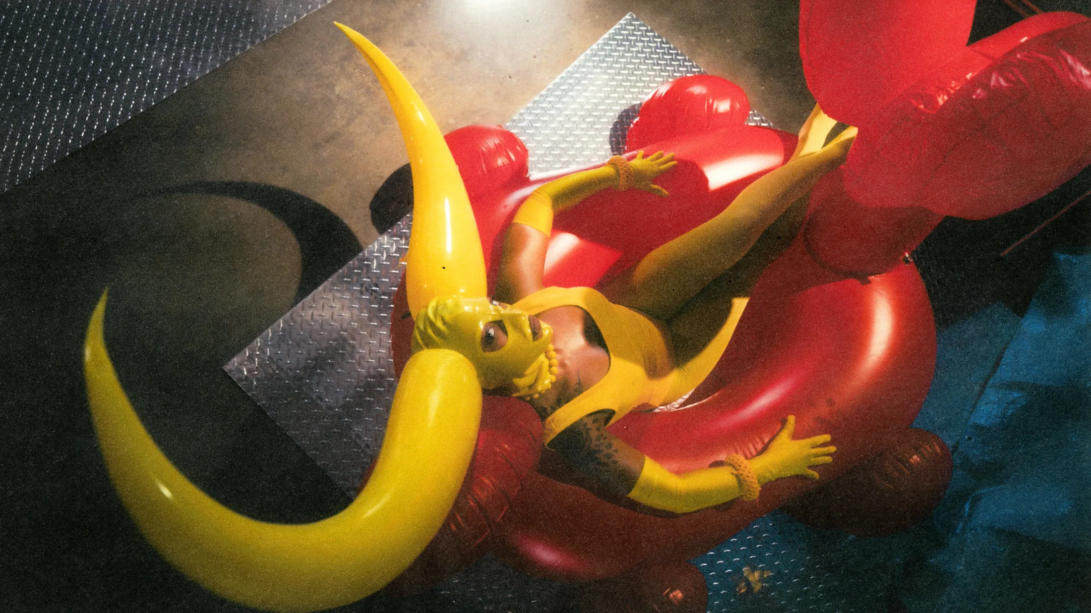 Yellow horned figure reclining on red inflatable rings and diamond plate